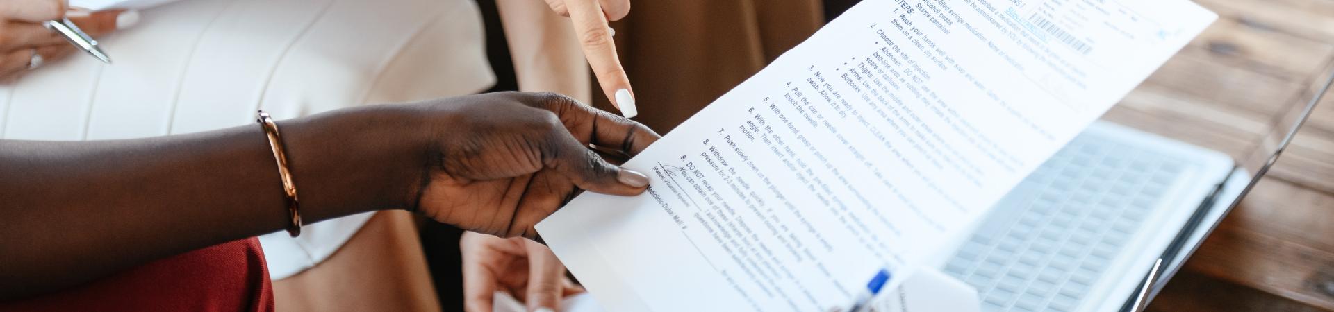 Close up of hands holding paper and people reviewing together